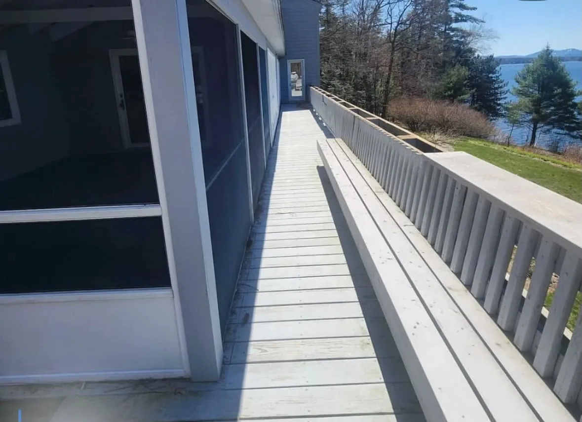 Weathered gray deck walkway beside the screened porch, looking out to the lake