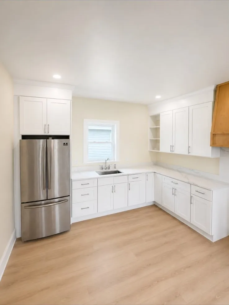 Corner of the finished kitchen with the sink under the window and quartz counters