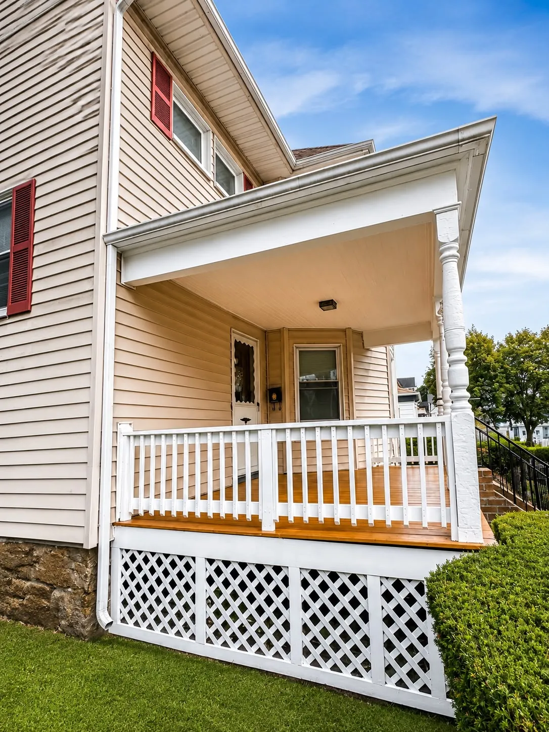 Finished porch from the side, with fresh white lattice below the deck and a stained floor above