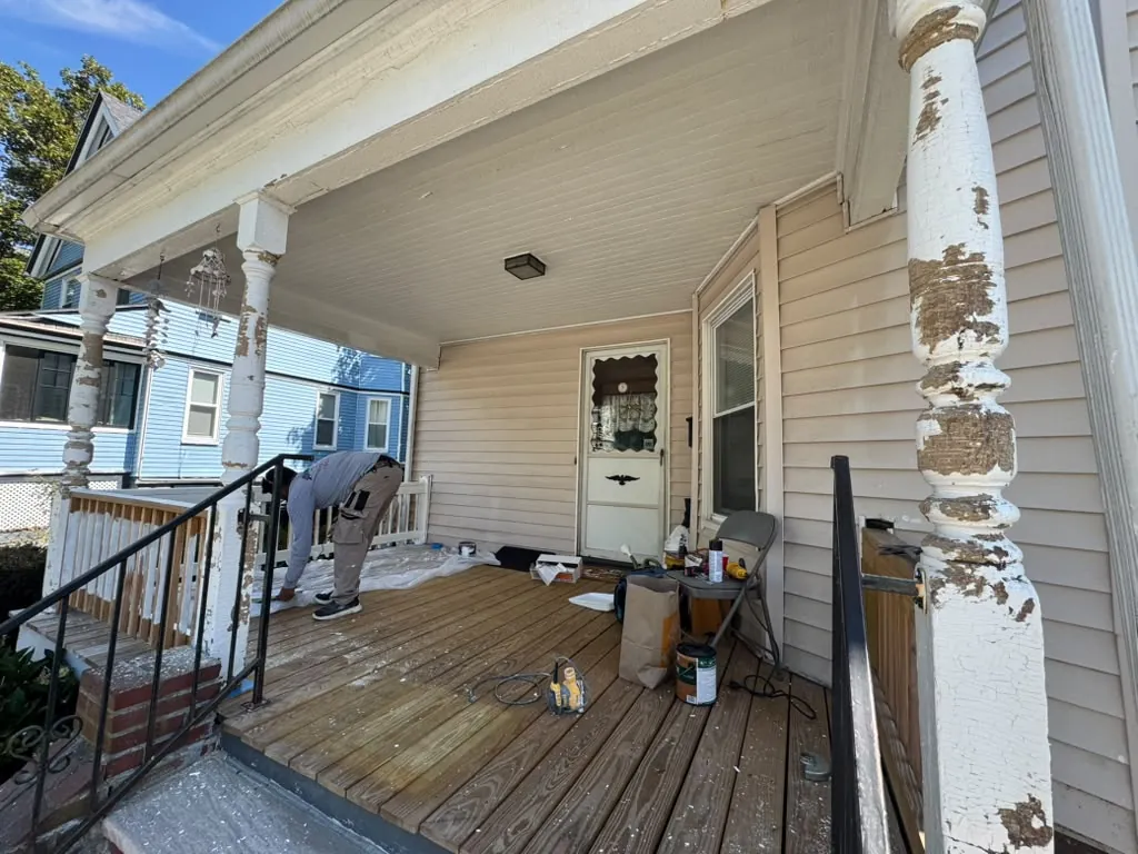 Front porch before the work, with paint peeling off the turned columns and a worn deck floor