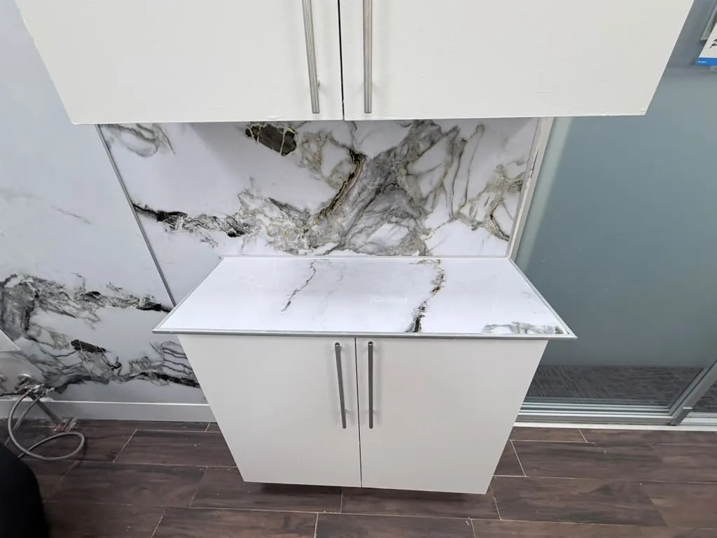 Counter and wall cabinets finished in white against the marble-look porcelain
